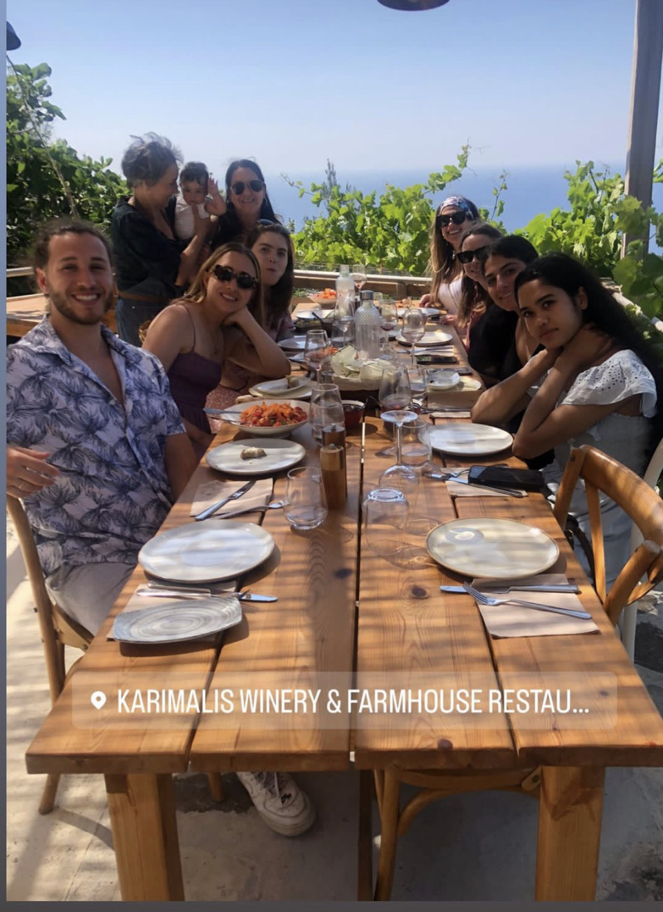 Nutrition sciences and nursing students in Greece at a long dining table over looking the ocean.